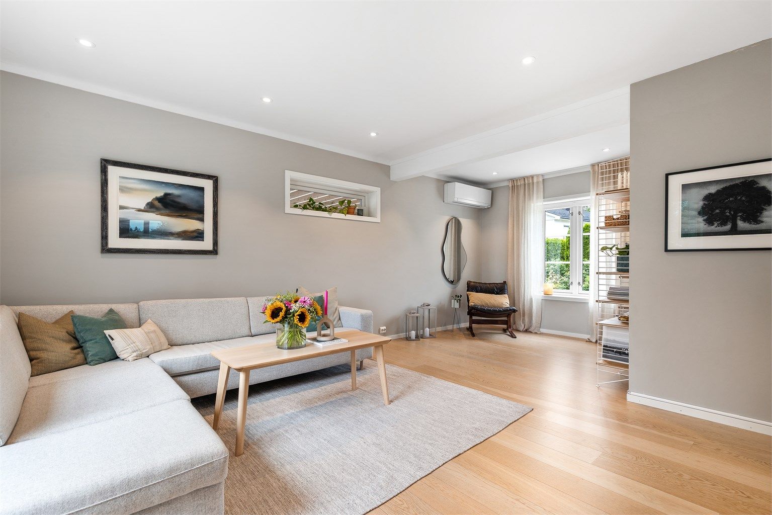 Romslig stue med plass til sittegruppe og TV-område. Fra stuen er det åpent mot spisestuen og kjøkkenet, noe som skaper en sosial atmosfære når man er med venner eller familie.