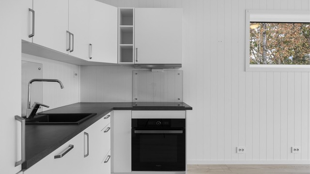 Kjøkkeninnredningen har over- og underskap med glatte fronter og stekeovn under platetoppen.