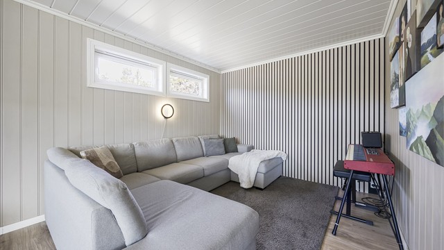 En del av stuen er innredet som en lun TV-krok, med en moderne spilevegg som et dekorativt element.
