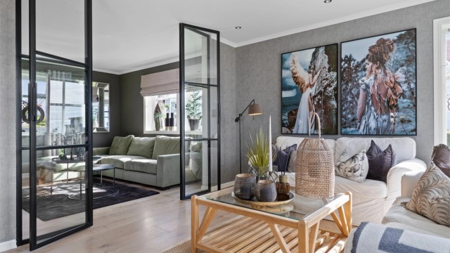 Glassdøren har et moderne design med sort innramming, og stuen innenfor er en koselig tv-stue der man enkelt trekker seg tilbake forlitt egentid med en god bok eller film.