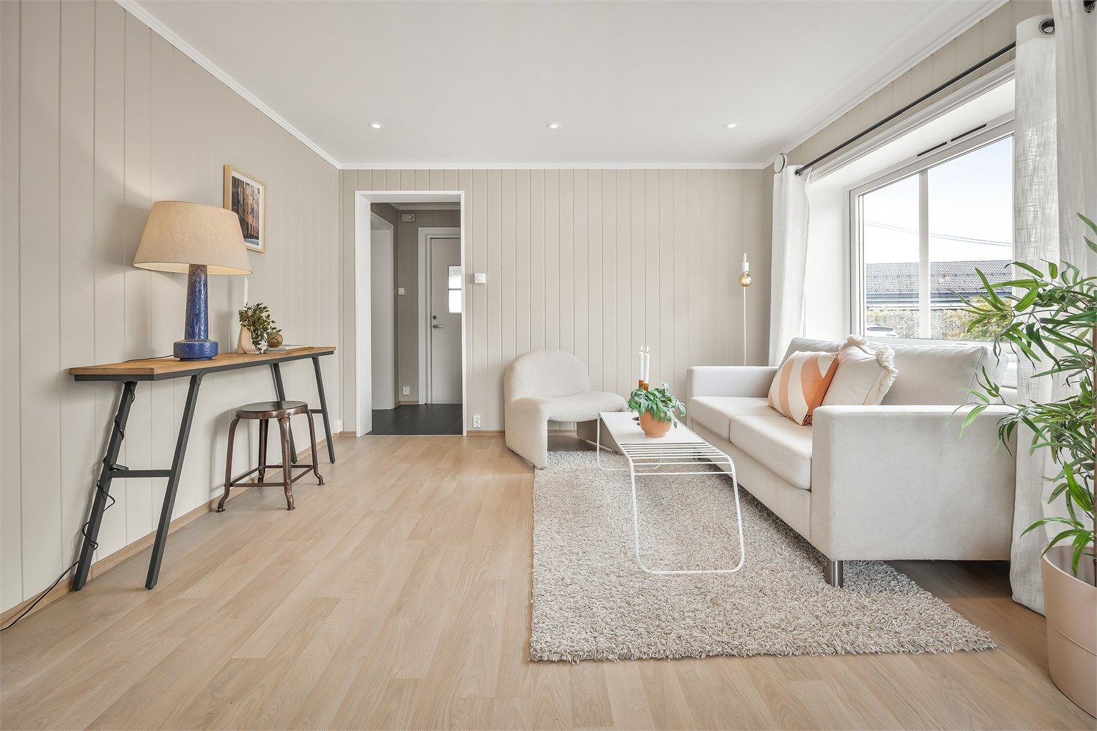 Lys stue med sofaområde og spiseplass.