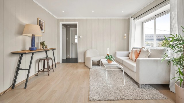 Lys stue med sofaområde og spiseplass.