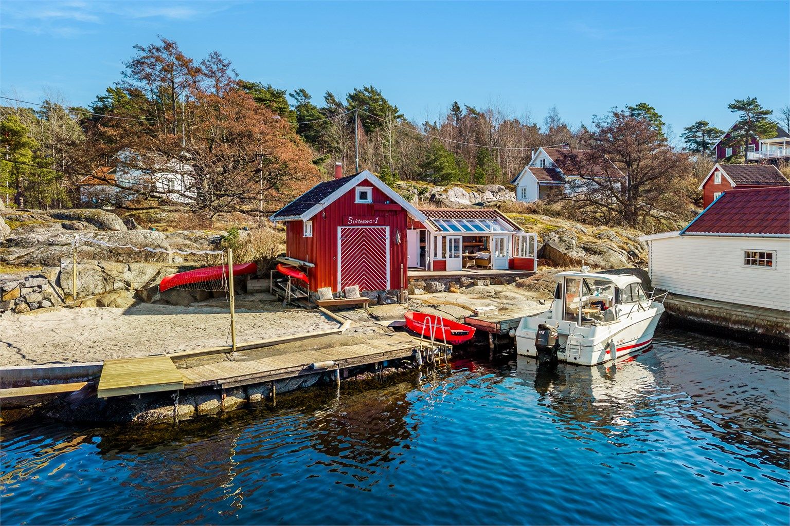 Skjerdgårds idyll med svaberg, brygge, sol, utsikt og en volleyball bane.