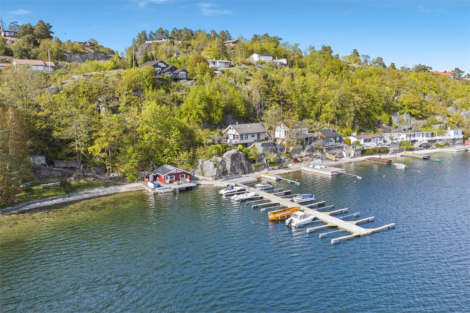 Fin sandstrand og bryggeanlegg med mulighet for å leie båtplass.