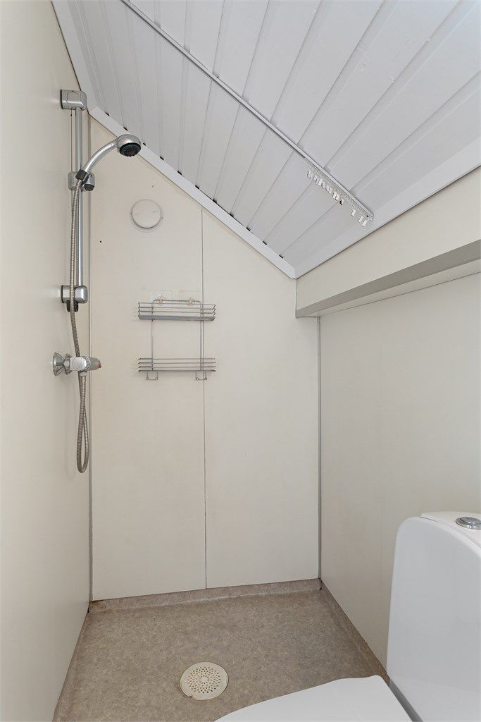 Dusjsonen er plassert under skråtaket, med veggmontert dusjbatteri og sluk i gulvet.