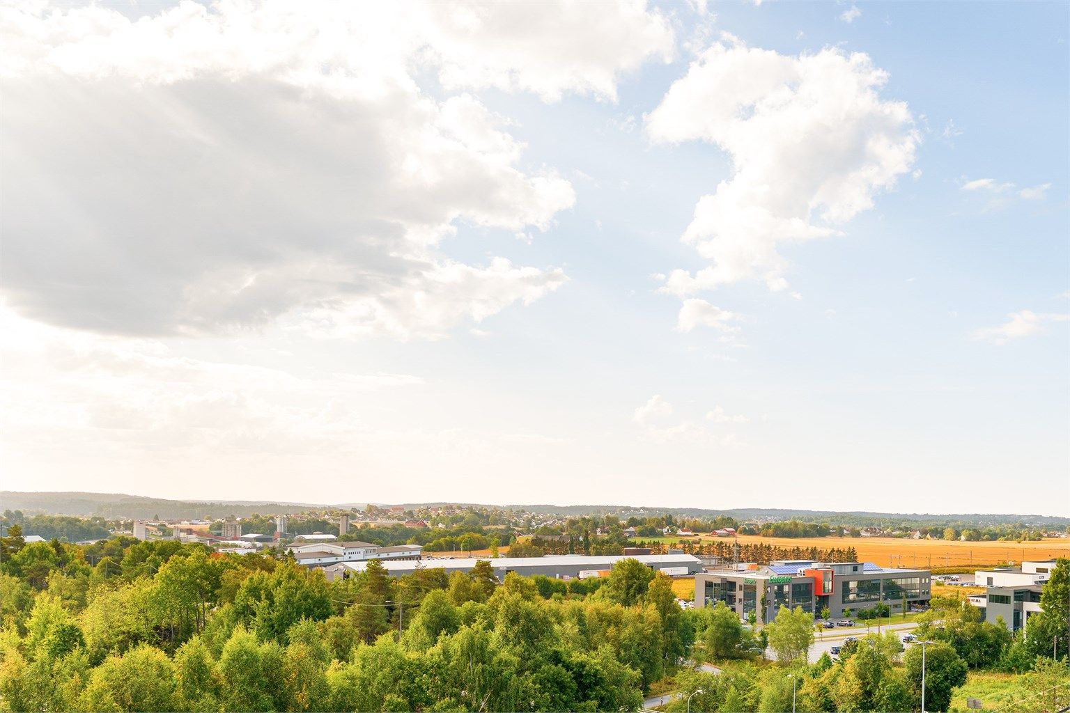 Vid og langstrakt utsikt fra balkongen, over åkerlandskap til skogkledde åser i det fjerne.