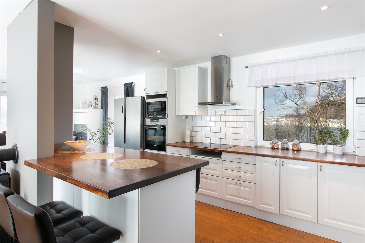 Kjøkkeninnredning med  profilerte fronter og benkeplate av  heltre. Praktisk kjøkkenhalvøy med sitteplasser mot stuedel