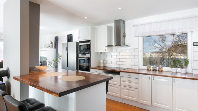 Kjøkkeninnredning med profilerte fronter og benkeplate av heltre. Praktisk kjøkkenhalvøy med sitteplasser mot stuedel