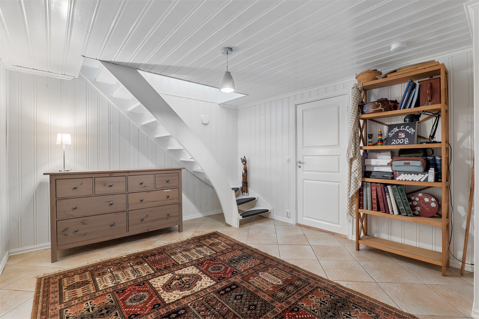 Innvendig trapp leder direkte mellom entreen og underetasjens romslige gang. Ved gangen finnes et soverom som er naturlig tilknyttet boligens hoveddel.
