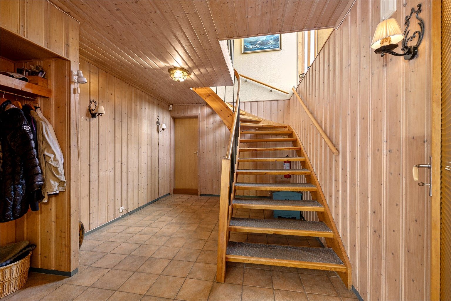 Fra vindfanget leder en tretrapp med teppebelagte trinn opp til hovedetasjen.