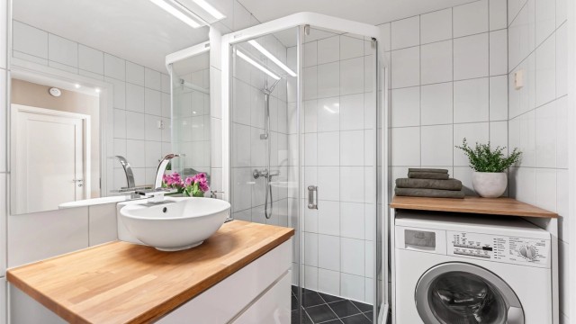 Flislagt bad med termostatstyrt gulvvarme, dusjhjørne med skyvedører og opplegg for vaskemaskin.