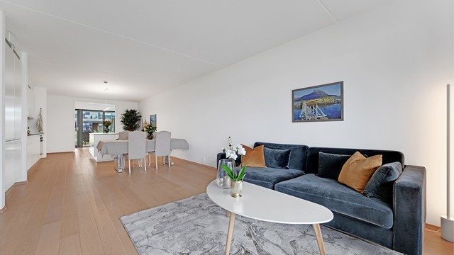 Romslig stue med god plass til sittegruppe og naturlig overgang mot spiseplassen.