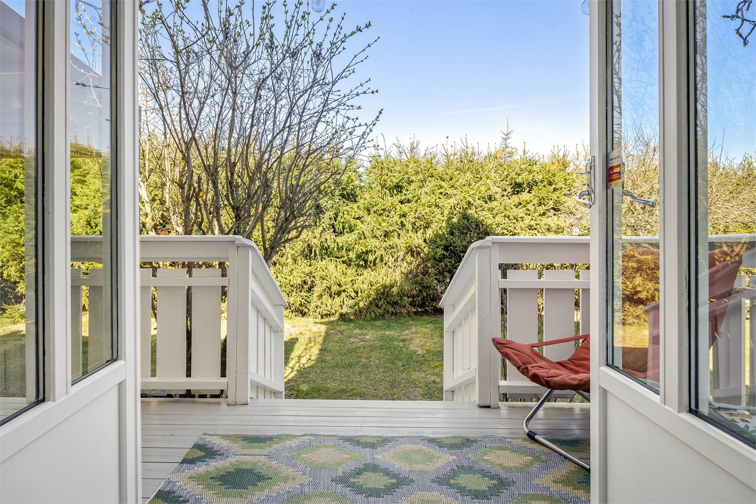 Fra balkongen ved spisestuen er det trapp ned til den store plattingen og hagen.