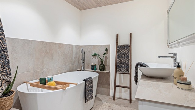 Badekaret er plassert i hjørnet med flislagte vegger og tilhørende armatur.