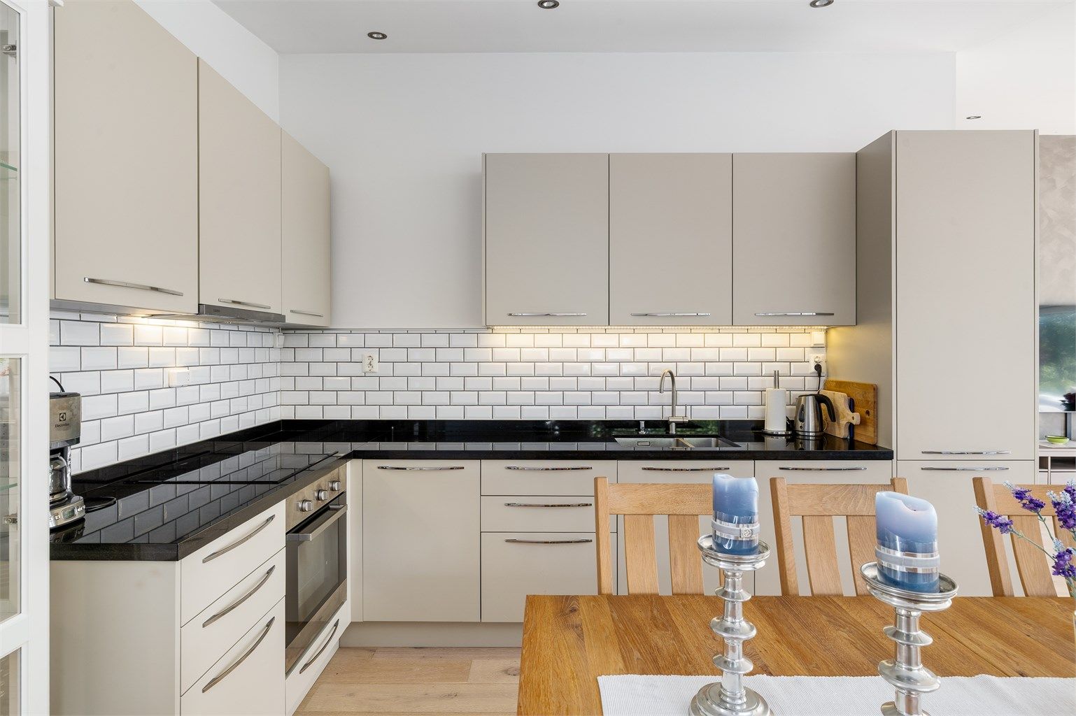 Kjøkkeninnredningen har slette fronter og metroflis mellom benk og overskap. Benkeplaten av slipt stein.