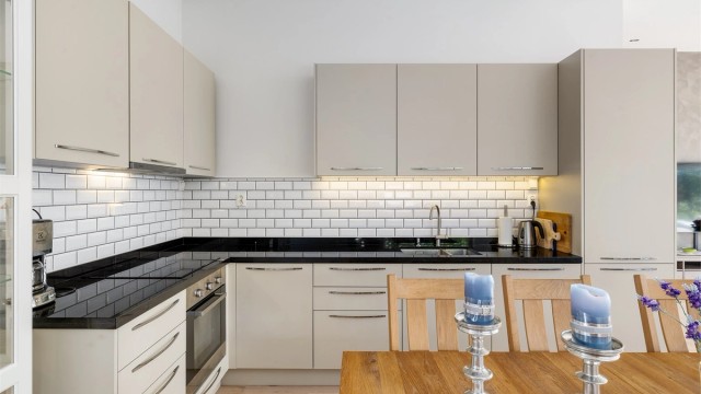 Kjøkkeninnredningen har slette fronter og metroflis mellom benk og overskap. Benkeplaten av slipt stein.