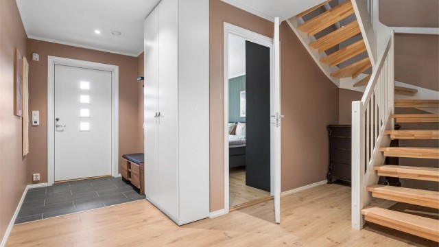 Den romslige entréen tar deg godt imot, med flislagt gulv, gulvvarme og garderobeskap.