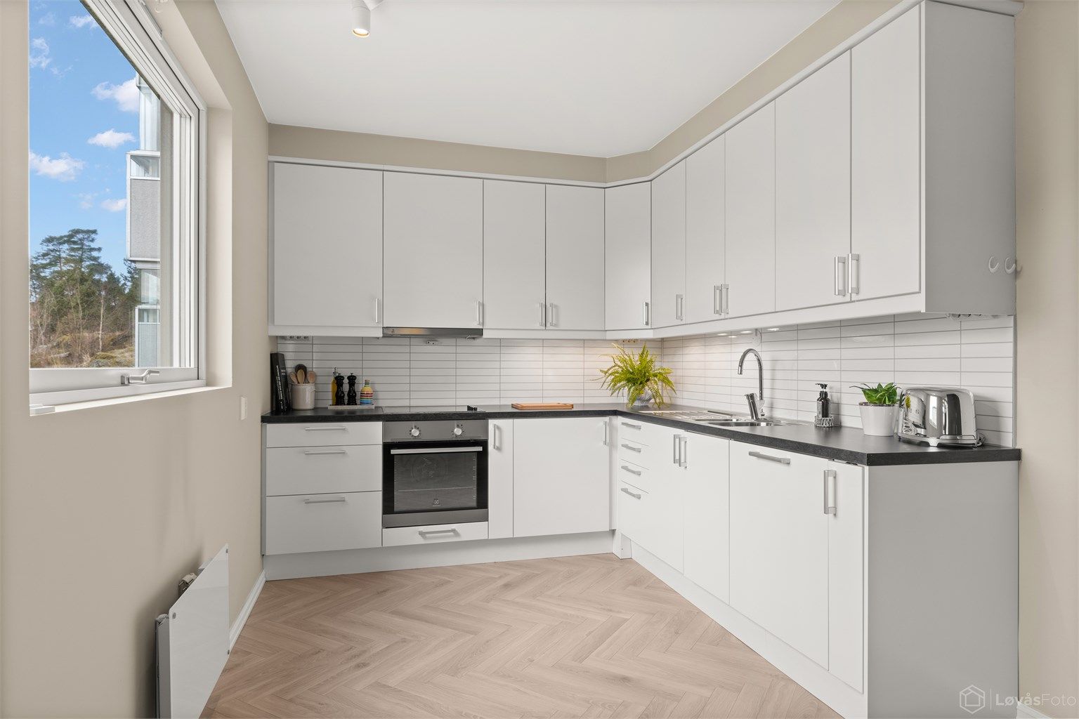 Kjøkken med 1-stavs fiskebenslaminat og plass til spisebord ved vinduet