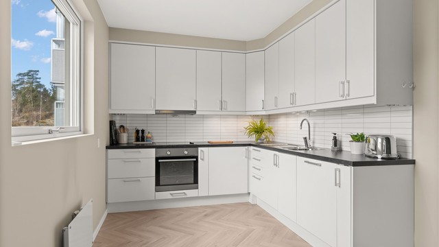 Kjøkken med 1-stavs fiskebenslaminat og plass til spisebord ved vinduet