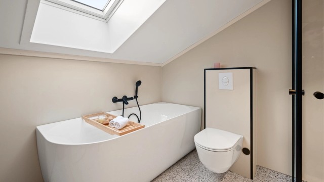 Rommet er utstyrt med både badekar og et separat dusjhjørne med svingbare glassdører.