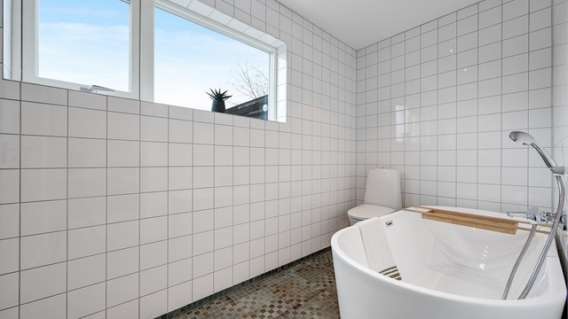 Badet i denne etasjen er helfliset, har gulvvarme og et frittstående badekar.