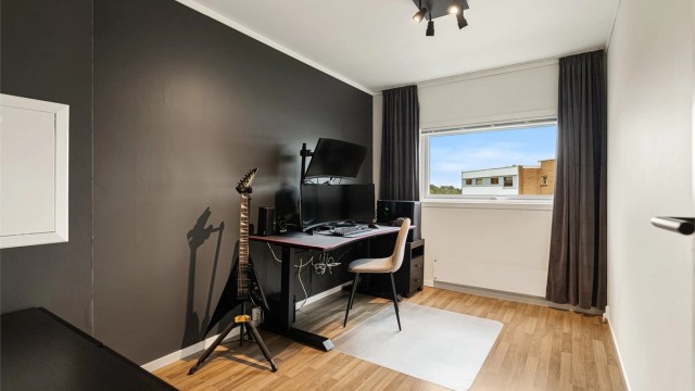 Soverom nummer to er innredet som kontor, med laminat på gulv og malte slette flater.