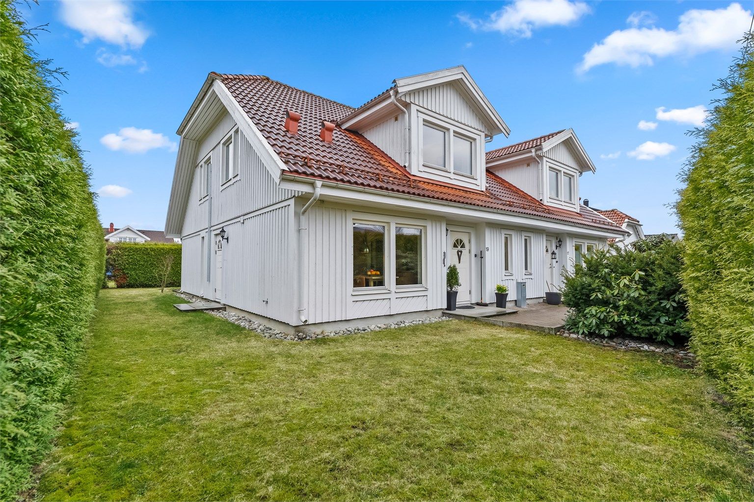 Boligen har et hyggelig inngangsparti i grønne omgivelser.