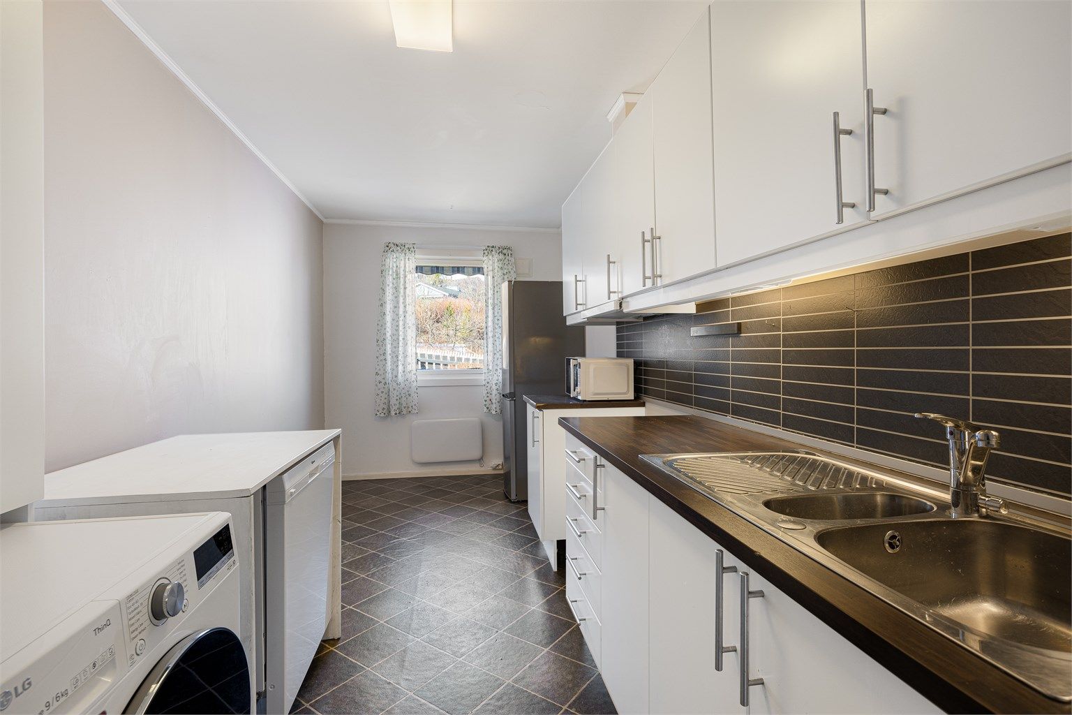 Praktisk kjøkken med laminert benkeplate og opplegg for vaskemaskin.