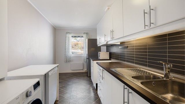 Praktisk kjøkken med laminert benkeplate og opplegg for vaskemaskin.