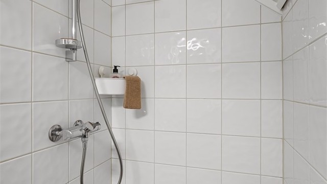 Varme i gulv og utstyrt med gulvstående toalett, dusjnisje og servant med skap under og speil med belysning over