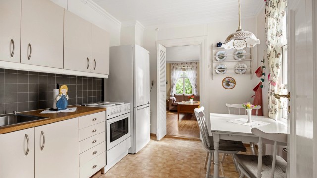 Kjøkken i første etasje med glatte fronter, laminert benkeplate og plass til spisebord.