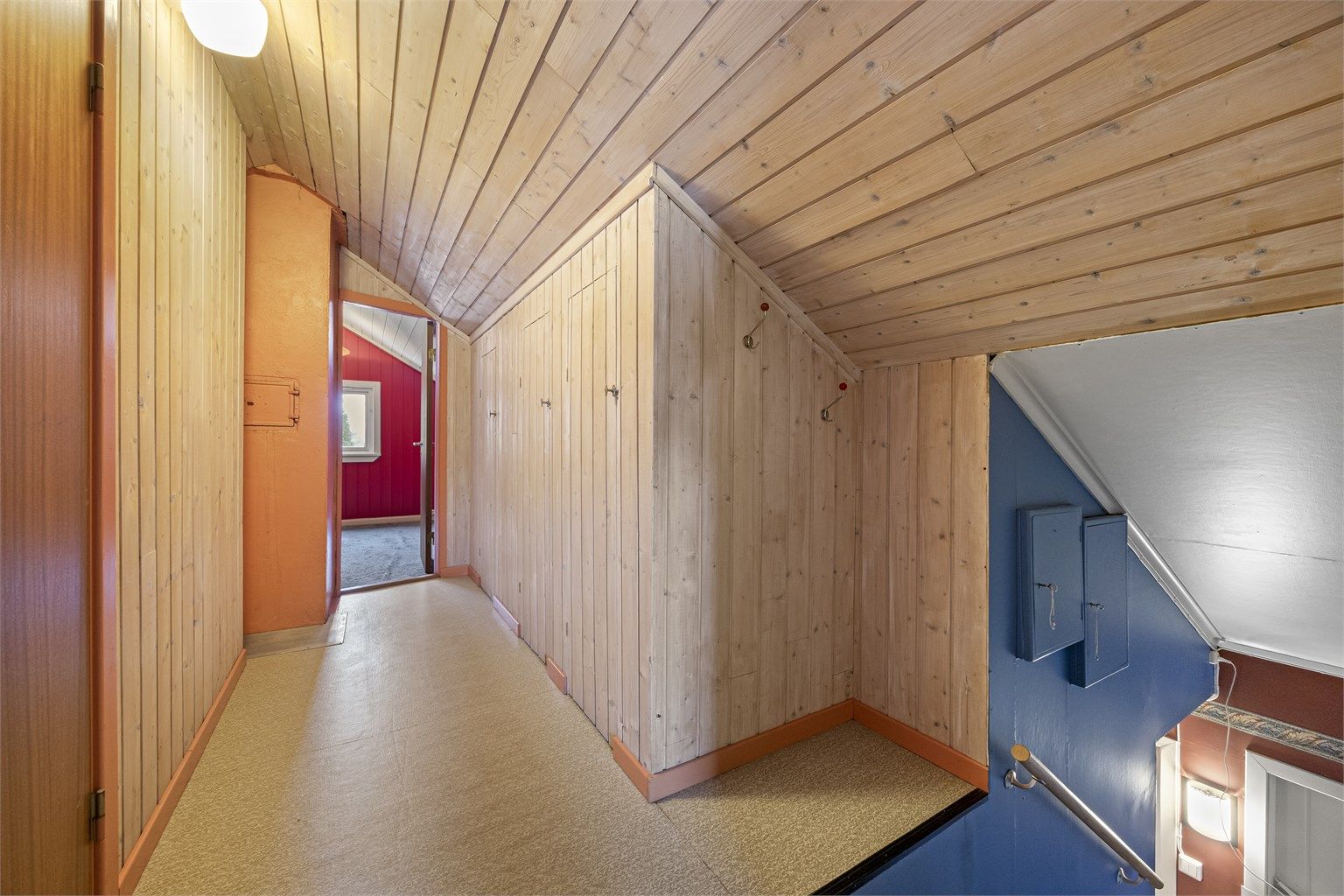 En tretrapp leder opp til loftsetasjen, som har panelkledde vegger og tak.
