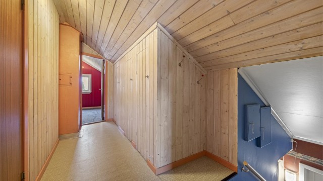 En tretrapp leder opp til loftsetasjen, som har panelkledde vegger og tak.
