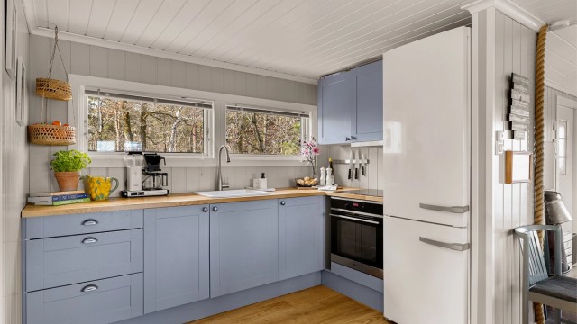 Kjøkkeninnredning med profilerte fronter, porselensvask, ventilator og integrert komfyr.