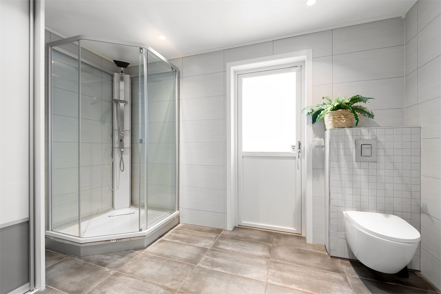 Badet har gulvvarme, vegghengt toalett og dusjkabinett.