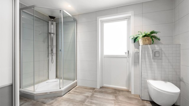 Badet har gulvvarme, vegghengt toalett og dusjkabinett.