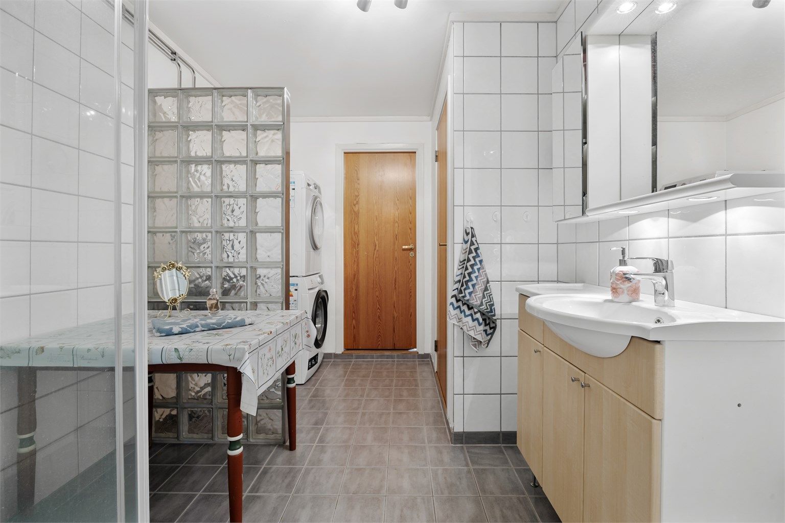 Badet i første etasje har flislagt gulv, dusjkabinett og en romslig innredning med servant.