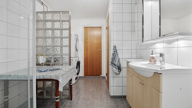 Badet i første etasje har flislagt gulv, dusjkabinett og en romslig innredning med servant.