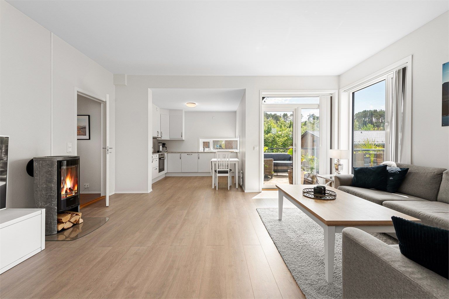 Åpen stue og kjøkkenløsning med lyse overflater og godt med naturlig lysinnslipp fra vinduer