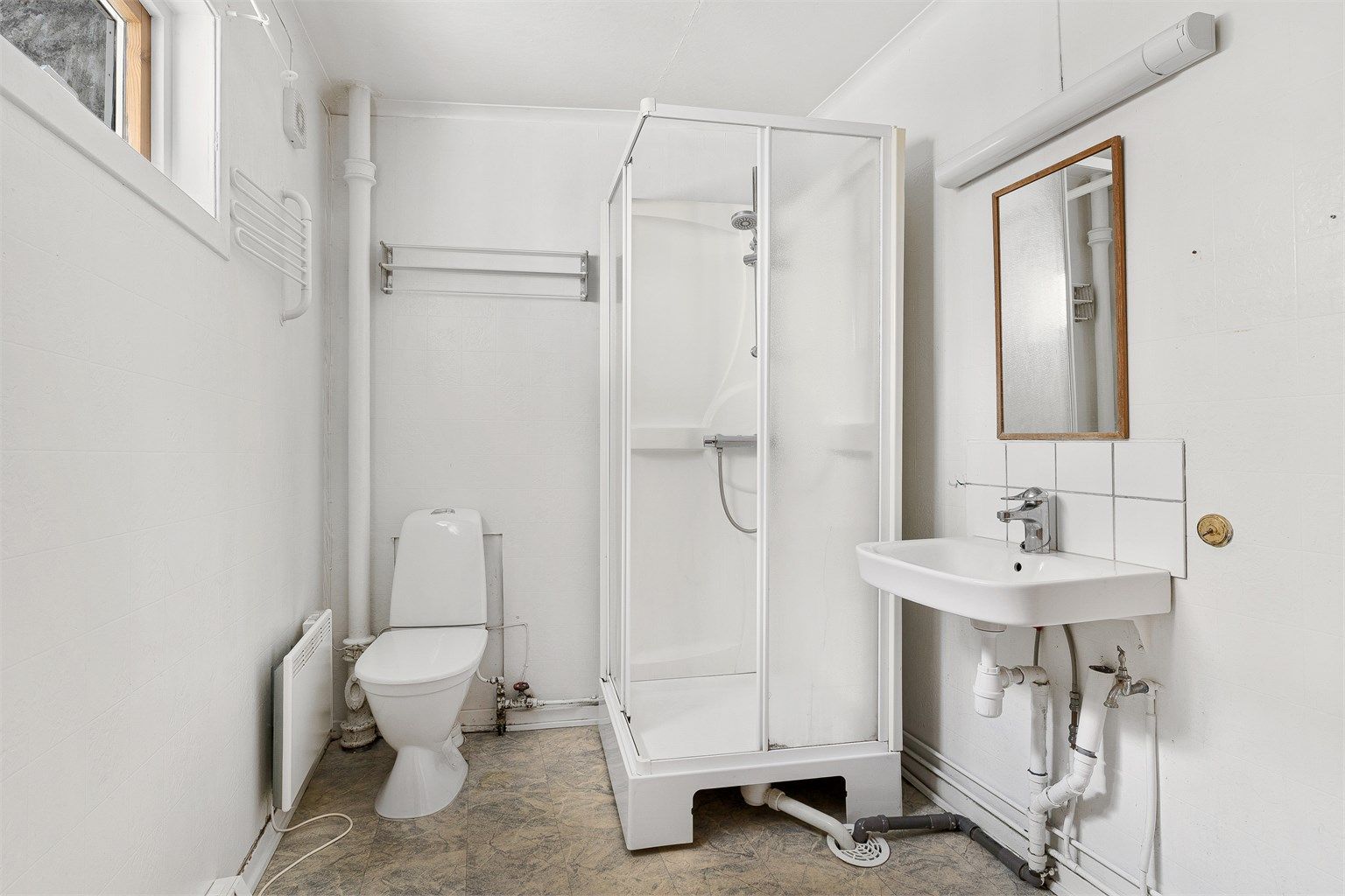 Badet er enkelt og inneholder wc, dusjkabinett og servant.