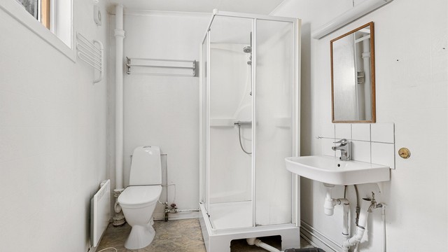 Badet er enkelt og inneholder wc, dusjkabinett og servant.