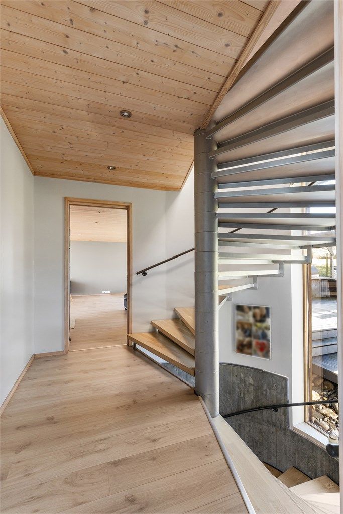 En elegant spiraltrapp i tre og metall forbinder etasjene og fungerer som et skulpturelt element i boligen.