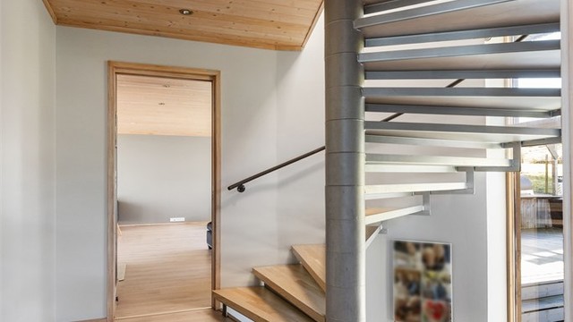 En elegant spiraltrapp i tre og metall forbinder etasjene og fungerer som et skulpturelt element i boligen.