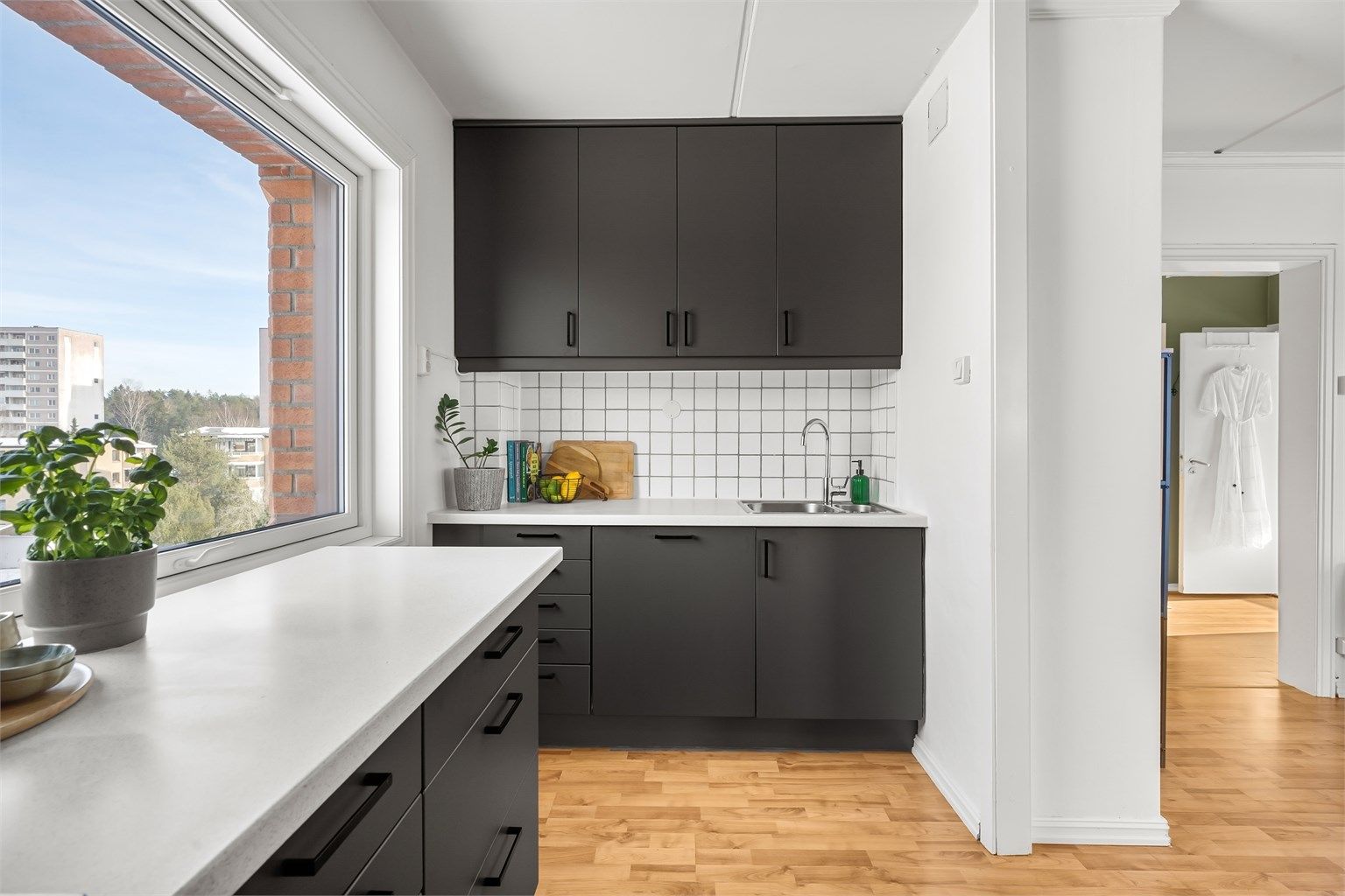 Laminert benkeplate med nedfelt vask og fliser mellom benk og overskap.