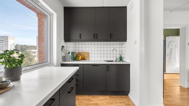 Laminert benkeplate med nedfelt vask og fliser mellom benk og overskap.