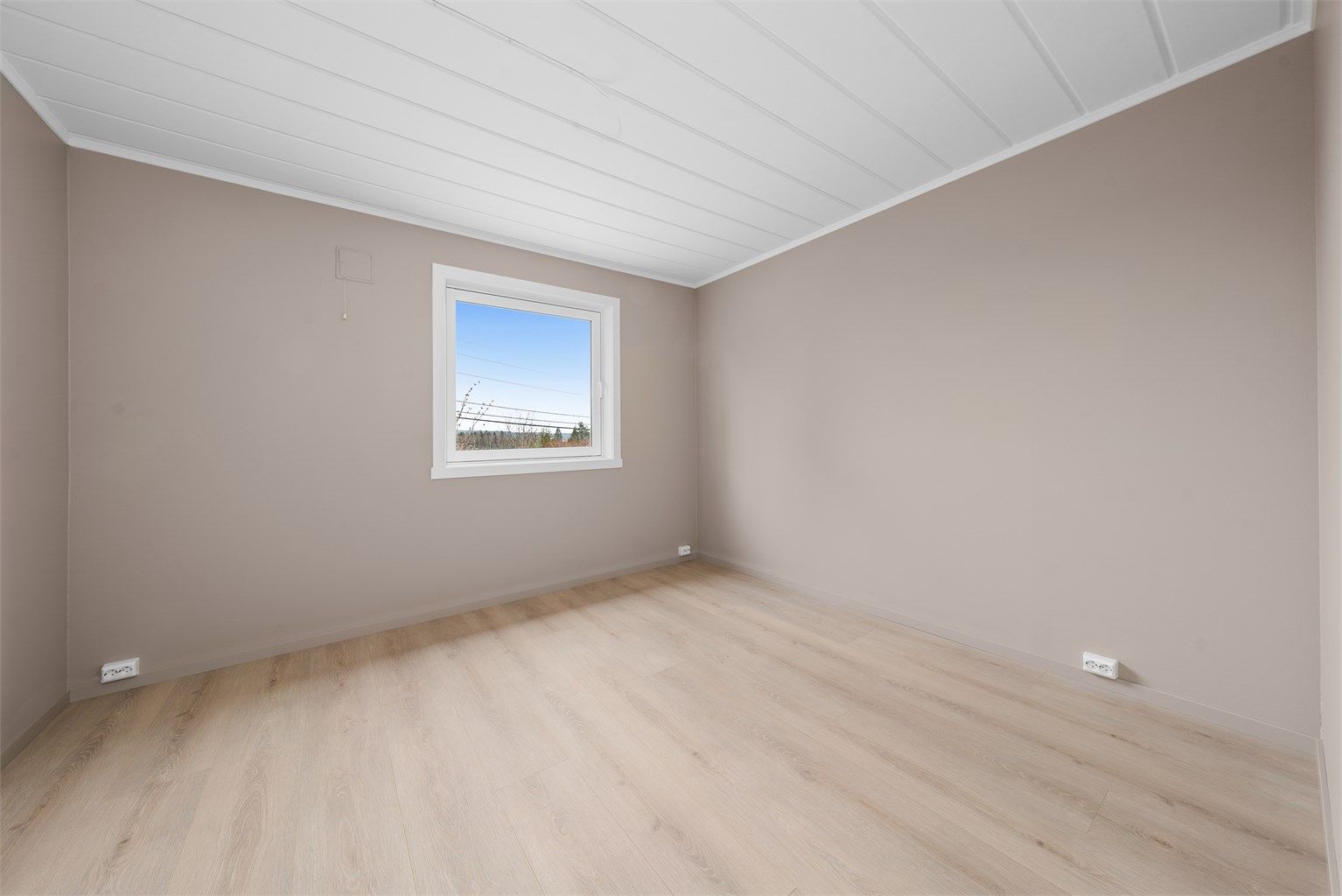 Rommet har malte, glatte flater og laminat på gulvet.