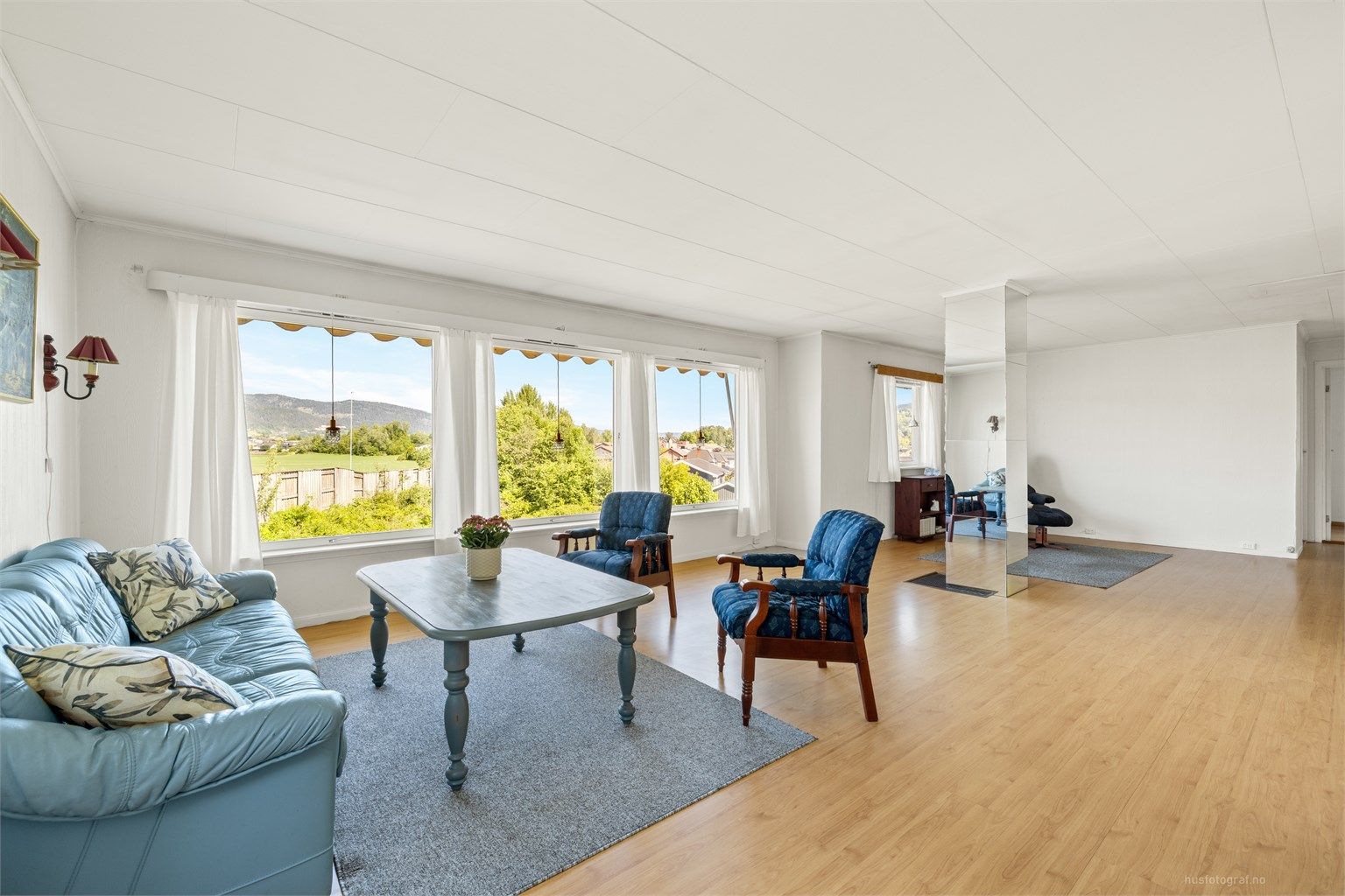 Lys og romslig vinkelstue med sofaområde, sittegruppe og spiseplass