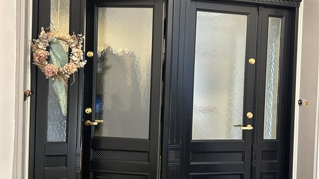 Ny inngangsdør av tre med glassfelt, brannklasse Ei30 og lydklasse 35 dB, skiftet i 2024.