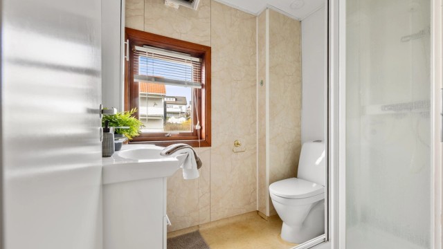 Bad er av eldre stander og har belegg på gulv og våtromsplater på vegg. Det er servant, toalett og dusjkabinett.