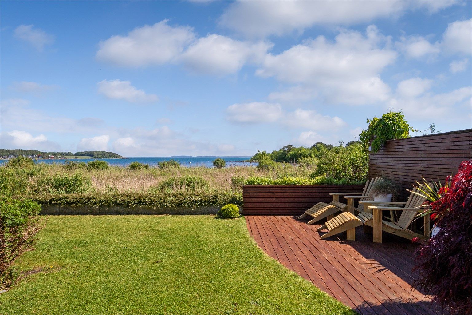 I hagen på nedsiden er det bygd en fin markterrasse helt i hjørnet, nærmest savannen . Denne har dekke av tre, skjermende levegger i bakkant og et areal på ca. 9 kvm. Leveggene er utstyrt med blomsterkasser slik at man kan få en ekstra frodig uteplass.